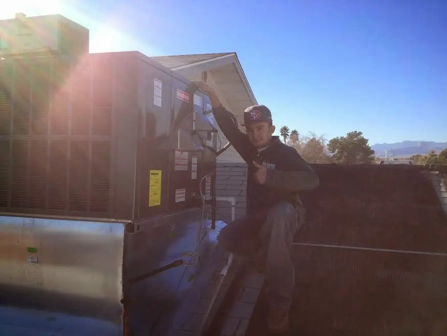 HVAC technician performing AC Tune-Up on a rooftop unit in Hesperia